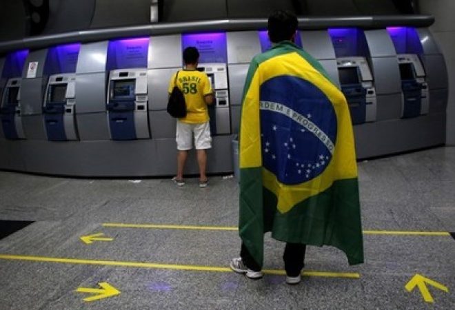 Pessoas sacam dinheiro em caixa eletrônico de banco em São Paulo