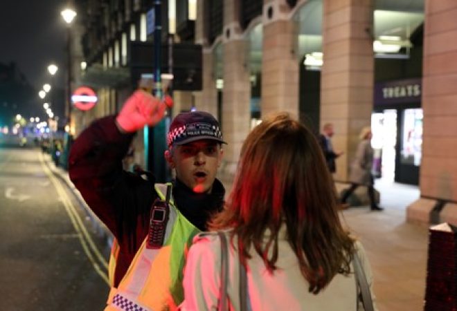 Agente policial conversa com mulher próximo ao Parlamento no momento em que a polícia investiga pacote suspeito, no centro de Londres