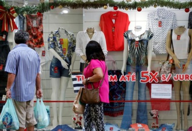 Consumidores passam por vitrine de loja em São Paulo