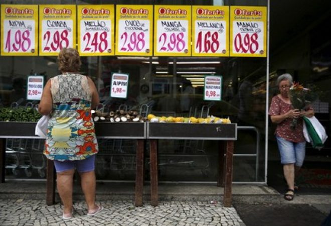 A woman looks on prices at a food market in Rio de Janeiro