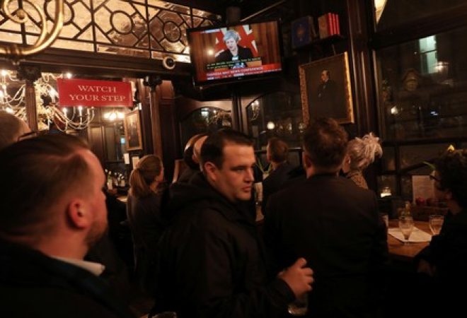 Clientes de pub de Londres acompanham entrevista coletiva de premiê britânica, Theresa May, pela televisão