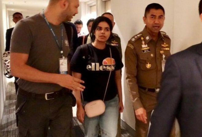 Jovem saudita Rahaf Mohammed al-Qunun caminha ao lado de autoridades imigratórias da Tailândia dentro do aeroporto de Bangcoc