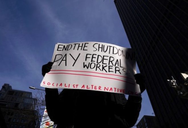 Manifestante segura uma placa durante protesto contra a paralisação parcial do governo em frente a um prédio público federal fechado em Nova York