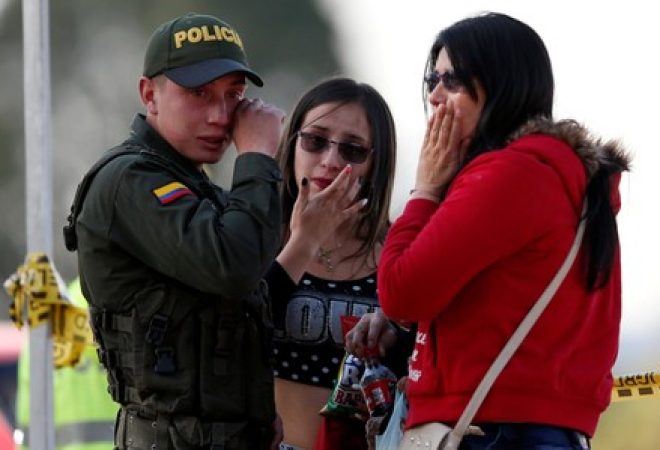 Policial e duas mulheres choram perto do local de explosão de carro-bomba, de acordo com autoridades, em Bogotá