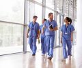 Four,Healthcare,Workers,In,Scrubs,Walking,In,Corridor