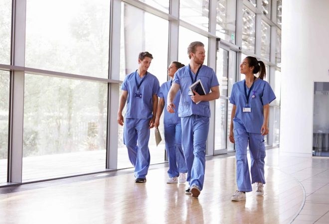 Four,Healthcare,Workers,In,Scrubs,Walking,In,Corridor