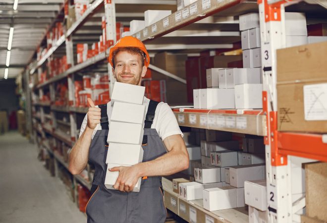 Industrial worker indoors in factory. Young technician with orange hard hat.