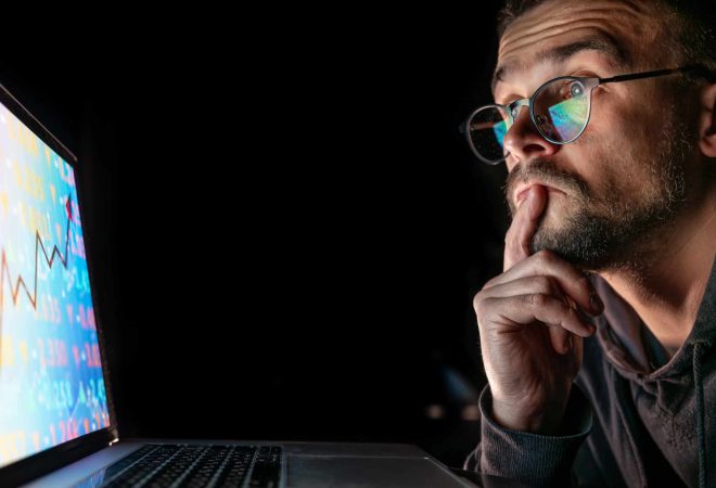 Serious business man trader analyst looking at a computer monitor, investor broker analyzing indexes, financial chart trading online investment data on cryptocurrency stock market graph on pc screen.