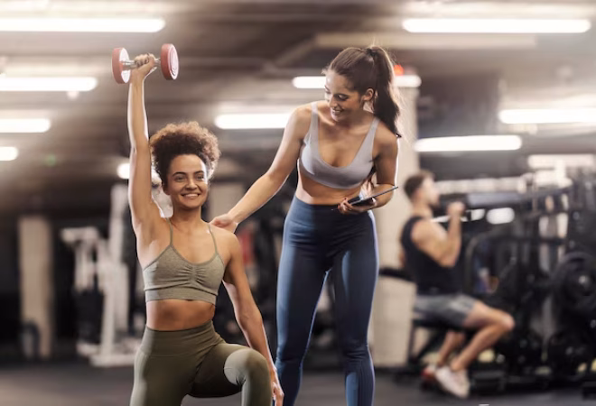 uma-desportista-esta-a-exercitar-se-com-halteres-e-o-treinador-pessoal-esta-a-encoraja-la_232070-23715