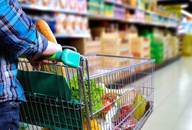 Man pushing shopping cart full of food in the supermarket aisle. Elevated rear view. horizontal composition