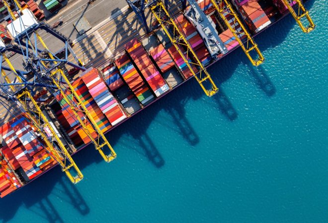 Aerial view of cargo ship and cargo container in harbor.