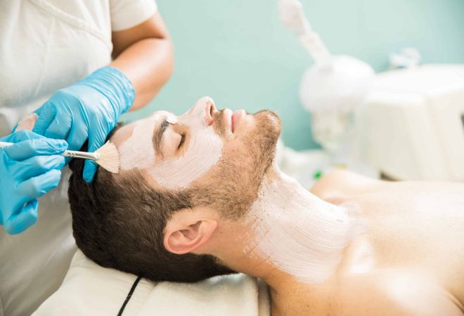 Profile view of a young man getting a moisturizing facial treatment in a health spa