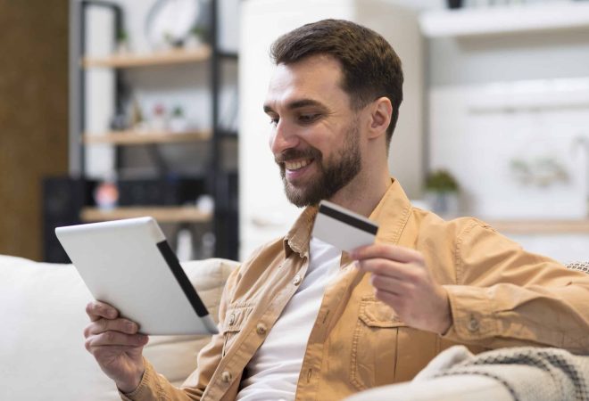 vista-lateral-homem-sorridente-segurando-o-tablet-e-cartao-de-credito
