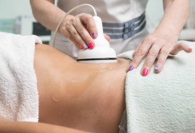 Woman getting ultrasound cavitation treatment by cosmetologist. female client enjoying anti-cellulite procedure at beauty salon. High quality photo