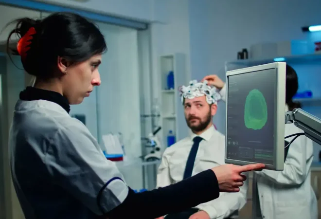 woman-researcher-looking-monitor-analysing-brain-scan-while-coworker-discussing-with-patient-background-about-side-effects