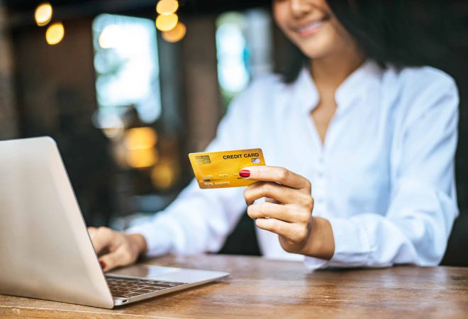 woman sat with a laptop and paid with a credit card in a coffee shop.